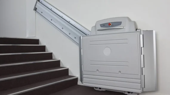 ACCESS BDD straight platform lift called the supra linea folding up against the wall creating a compact and discrete design at the bottom of the stairs.