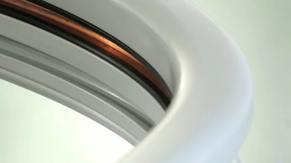 Close-up of curved white and silver surfaces with a visible copper strip, possibly part of a Supra Linea modern appliance or industrial equipment, set against a light background.