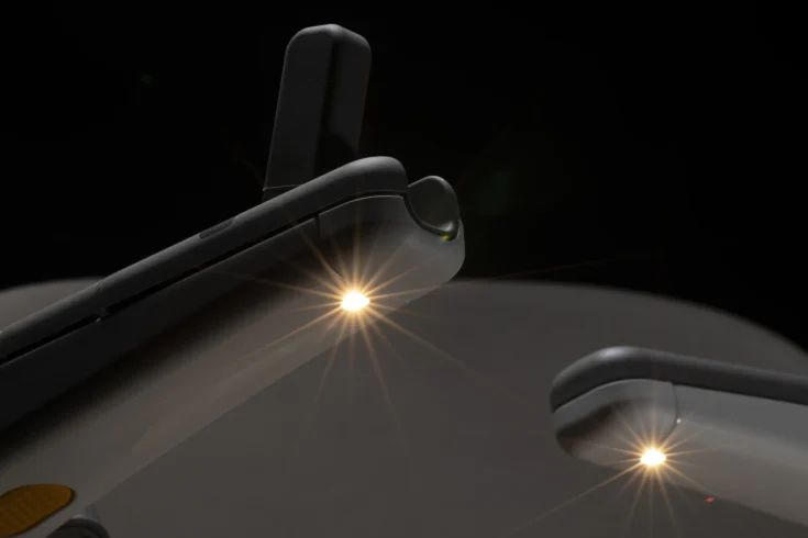Close-up view of a device, possibly a VR headset or smart glasses, featuring Light Assist technology with two illuminated sensors emitting light beams against a dark background.