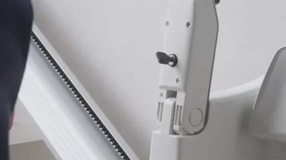 Close-up view of a HomeGlide Outdoor Stair Lift’s mechanical arm joint, featuring a visible gear track and adjustment knob, set against a plain background.