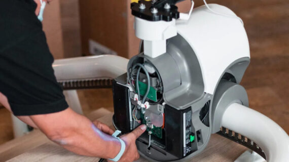 Technician servicing the motor and battery components of a curved stair lift during maintenance, highlighting the internal drive system and accessibility equipment repair.