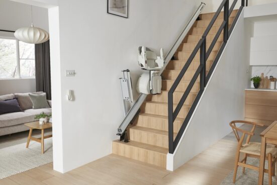 HomeGlide stairlift by ACCESS BDD demonstrating folding rail on a wooden staircase in a residential home.